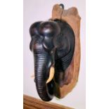An Anglo-Indian carved ebonised elephant wall plaque, circa 1916, with bone eyes and tusks. 51cm H