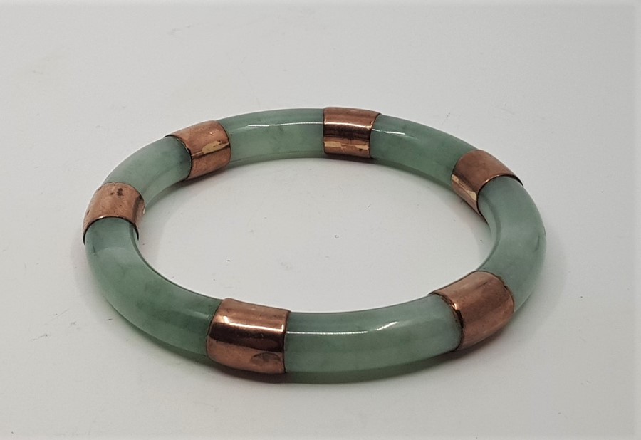 A jade slave bangle, c.1920's, with yellow metal mounts, external diameter 94mm. - Image 2 of 2