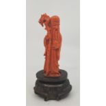 A Chinese carved coral figure: Lohan, to white metal inlaid carved wood stand, height 13.8cm