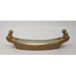 A ceramic boat form pen tray, in the manner of Coalport, with gilt winged figure head to either end,