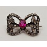 A Victorian precious metal, ruby and diamond "bow" brooch, set oval mixed cut ruby to centre (