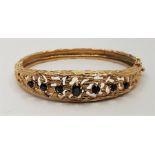 A 14ct. gold and sapphire set hinged bangle, c.1970's, of elliptical form with open work textured