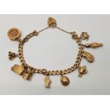 A 9ct. gold charm bracelet, flat curb link with 9ct. gold heart padlock clasp, suspending ten
