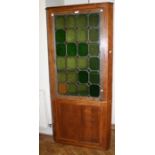 An early 20th century oak floor standing corner cupboard, with leaded stained glazed door enclosing