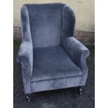 A late Victorian grey/blue plush upholstered country house deep seated wing back fireside chair on r