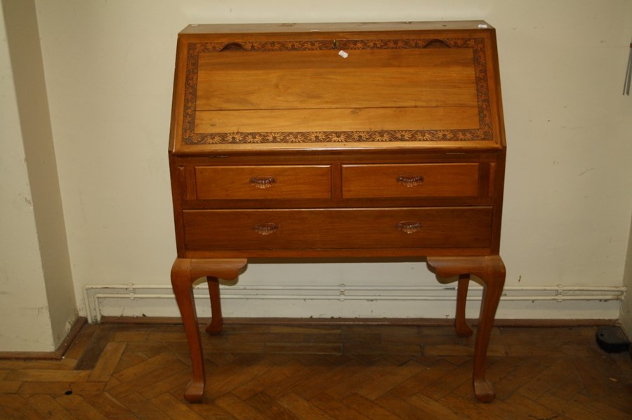 A mid 20th century Oriental teak bureau, the florally carved banded fall enclosing fitted interior o