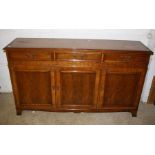 A reproduction Yew veneered and crossbanded low dresser fitted three drawers over ribbon frieze and