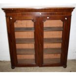 A Victorian mahogany bookcase, the moulded cornice over a pair of glazed doors enclosing three shelv