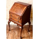 A Queen design crossbanded mahogany fall front bureau, opening to fitted interior above two