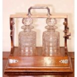 An early 20th century oak and silver plate Tantalus with a pair of glass carved decanters. 32cm H