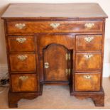A George I walnut and feather-banded kneehole desk, circa 1720, the half-veneered top cross and