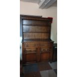 A 20th Century carved oak dresser with plate rack, moulded top with carved arched shape cornice,