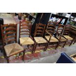 An early 20th Century set of six oak ladder back chairs, with rush seats, comprising five side