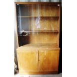 A mid 20th Century teak bookcase, of two-tiers, the upper section with two sliding glass doors,