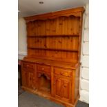 A traditional solid pine dresser with plate rack, the base with three drawers over two cupboards.
