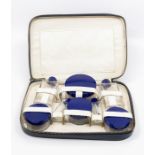 A 1930s cushioned vanity set, glass bottles with blue Bakelite lids
