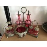 An Edwardian decanter stand with two cranberry glass decanters having silver plated cranberry