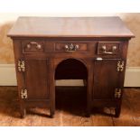 A George III revival oak kneehole desk, rectangular top above three frieze drawer over two cupboards