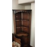 A 20th Century oak carved corner cupboard, three tier inverted serpentine shelves on a two