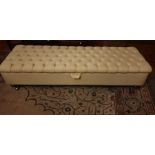 A Chesterfield type upholstered ottoman, raised on turned feet on castors.