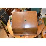 An Edwardian oak table-top stationary box, with sloping top opening to a fitted interior with manual