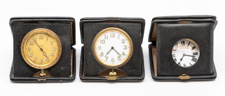 Three leather cased travel clocks, the eight day 'pocket watch' movements in square cases, 10.5cm (