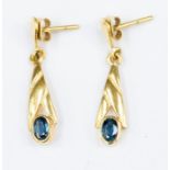 A pair of  sapphire and 18ct gold drop earrings, cross over design set to the bottom with oval cut