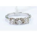 A three stone diamond 18ct white gold ring, composing three claw set round brilliant cut diamonds,