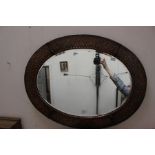 An Arts & Crafts Liberty & Co style brass framed oval mirror, mottled body, inset with floral and
