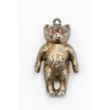 An Edwardian silver teddy bear pendant, engraved fur detail with red glass set eyes, hallmarked by