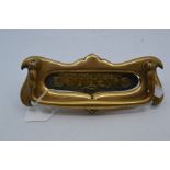 An Edwardian art nouveau brass door letter plate, circa 1900-1910, of double-scroll form, with