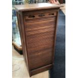 An early 20th Century oak tambour fronted shelving unit, panelled sides, the tambour front fitted