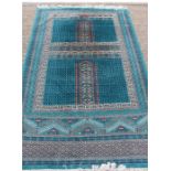 A large turquoise hand knotted woollen rug, with symmetrical decoration throughout