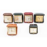 Six small leather cased travel clocks, the Swiss eight day movements in square cases, varying