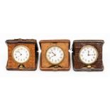 Three crocodile cased travel clocks, the eight day 'pocket watch' movements in square tan cases,