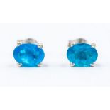 A pair of neon apatite and silver stud earrings, the oval stones approx. 7 x 5mm, four claw setting,