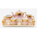 A Continental porcelain and gilt miniature tea set comprising teapot, pair of cups, sugar bowl and