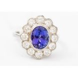 A tanzanite and diamond platinum ring, the central rub-over tanzanite weighing approx.. 3.