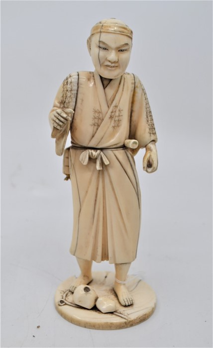 A Japanese sectional ivory figure of a farmer, Meiji period, modelled standing on a circular base,