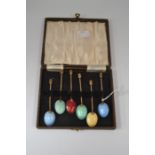 An early 20th Century set of six enamelled coffee spoons, in brass, boxed