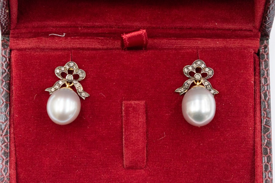 A pair of silver pearl and diamond stud earrings, the oval pearls approx. 11x  8mm suspended from