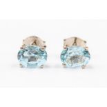 A pair of blue topaz and silver stud earrings, the oval sky blue topaz approx. 8 x 6mm, four claw