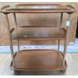 An Ercol ash and beech three tier tea trolley, each tier with gallery edges, and raised on beech
