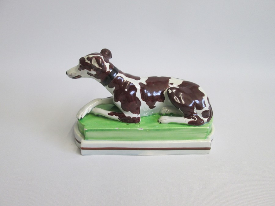 A Staffordshire model of a recumbent Greyhound/Whippet painted with brown markings, laying on a - Image 4 of 6