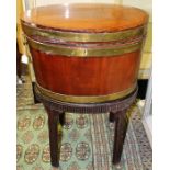 A George III mahogany and brass bound wine cooler, of oval form, fitted with carrying handle, raised