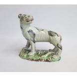 A Staffordshire Pottery Model of a Lioness, painted with grey markings  Standing on a green and