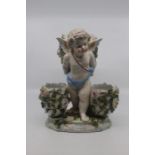 A Sitzendorf figural centrepiece, circa 1890-1900, modelled as a putti supporting three ovoid