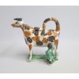 A Staffordshire Cow Creamer and Milk Maid. Sponge decorated in Ochre and brown, standing on a