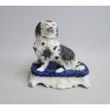 A Staffordshire porcelain Model of a Spaniel sitting on a blue cushioned tiered base Date: circa