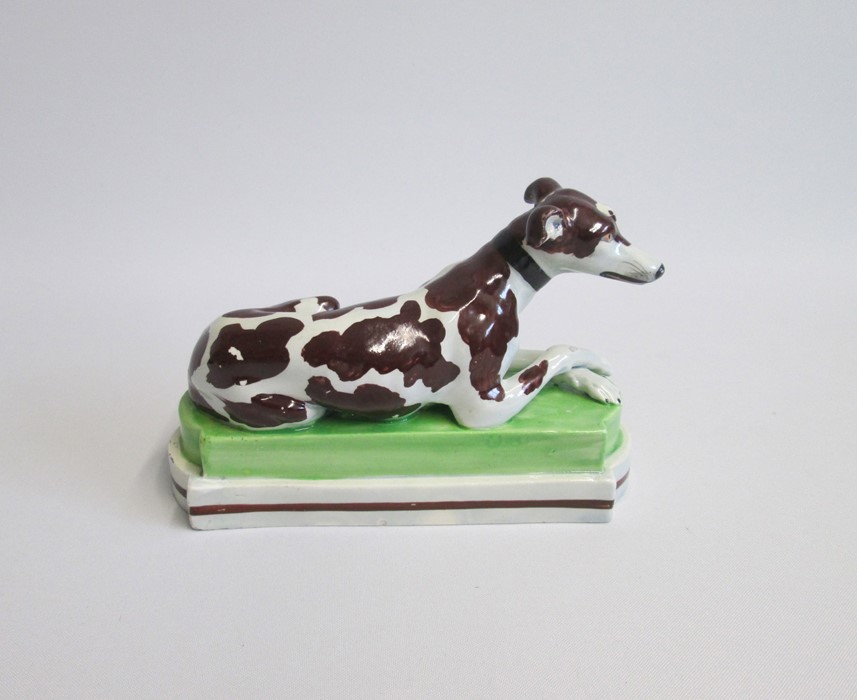 A Staffordshire model of a recumbent Greyhound/Whippet painted with brown markings, laying on a - Image 2 of 6